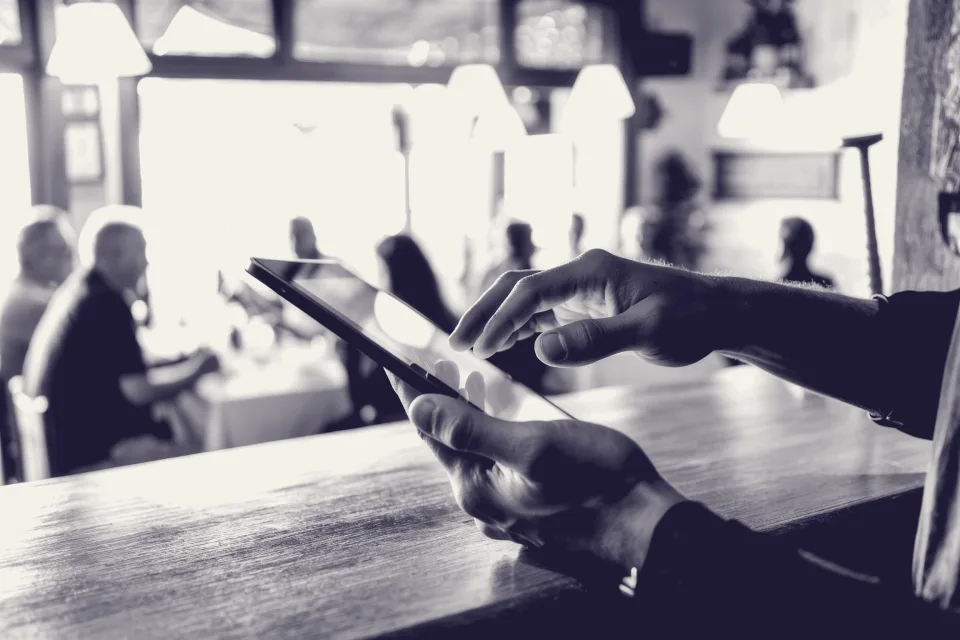 Manos de un camarero tomando una reserva en una tableta en la barra de un restaurante